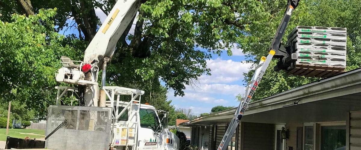 our delivery boom truck lifting shingles on to a house roof