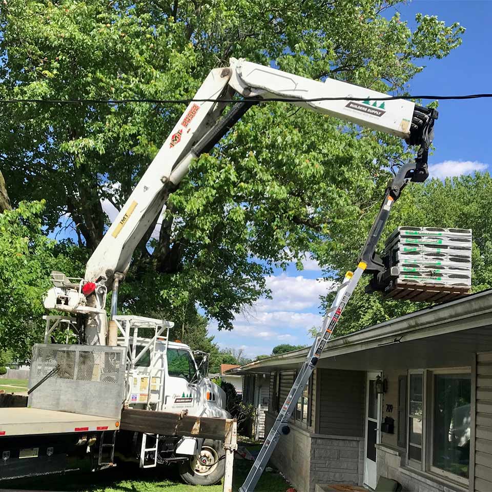 delivery truck lifting shingles onto a house roof
