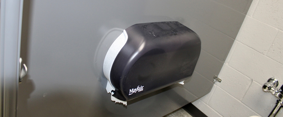 toilet paper dispenser attached to a stall wall in a bathroom