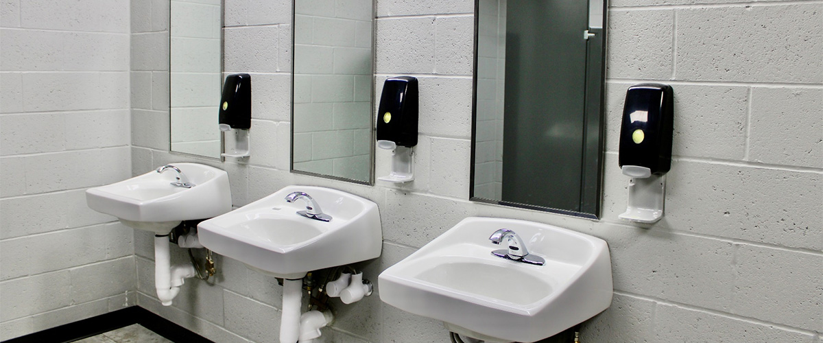 multiple sinks, mirrors, and soap dispensers hanging from the wall